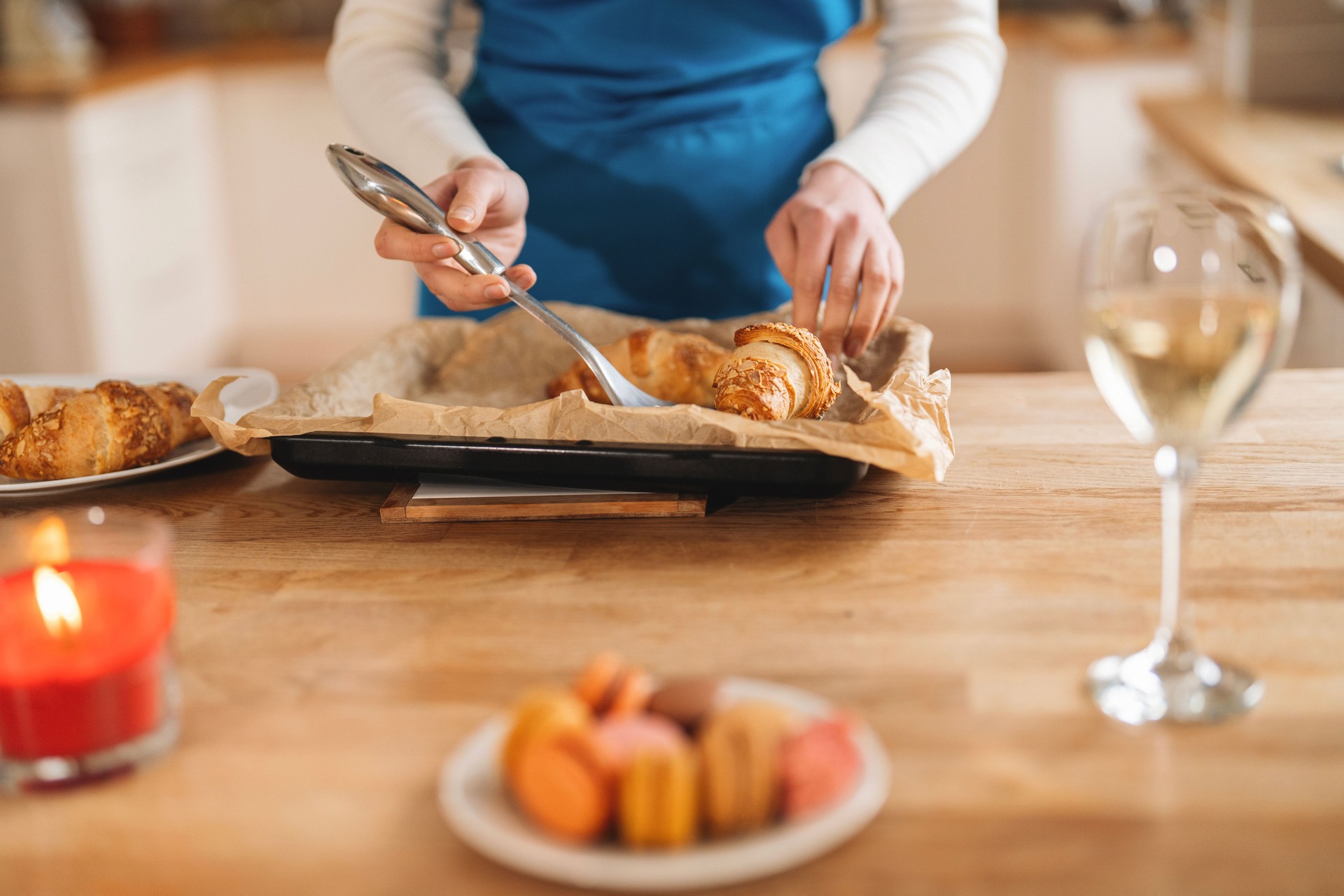 Baking fresh croissants in a cozy kitchen with a glass of wine and colorful macarons on the table during a relaxed afternoon gathering